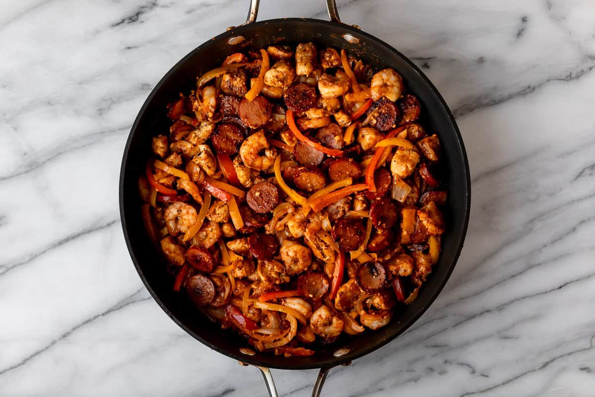 Keto jambalaya in a black skillet over a marble background.
