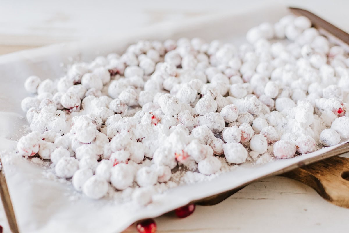 Sugared cranberries on a parchment paper lined baking sheet.