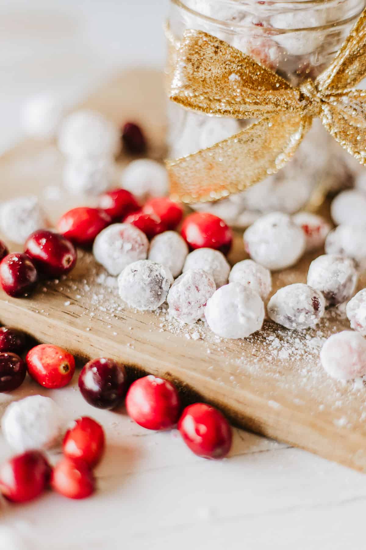 Close up of plain and candied cranberries on a wood board.