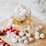 A jar of candied cranberries on a wood board with plain and candied cranberries around it with text overlay.