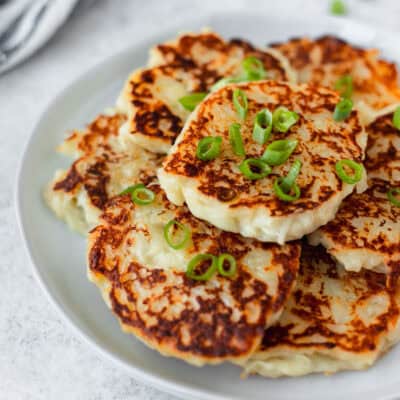 A plate of boxty, or Irish potato pancakes on a white plate garnished with scallions.