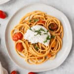 Overhead view of cherry tomato pasta topped with burrata cheese.
