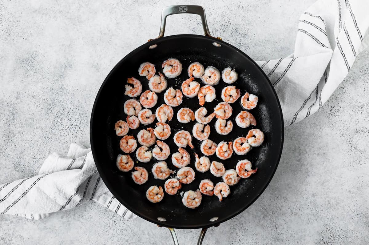 Shrimp in a large skillet over a light background.