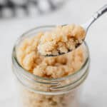 Streusel topping on a spoon held up over a jar filled with more.