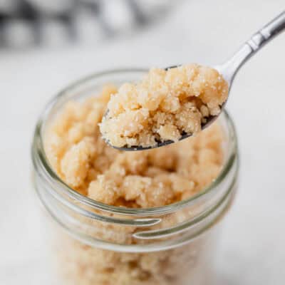Streusel topping on a spoon held up over a jar filled with more.