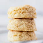 A stack of three buttermilk biscuits on a white plate with text overlay.
