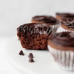 Mini brownie cupcakes on a stand with a bite taken out of one of them.