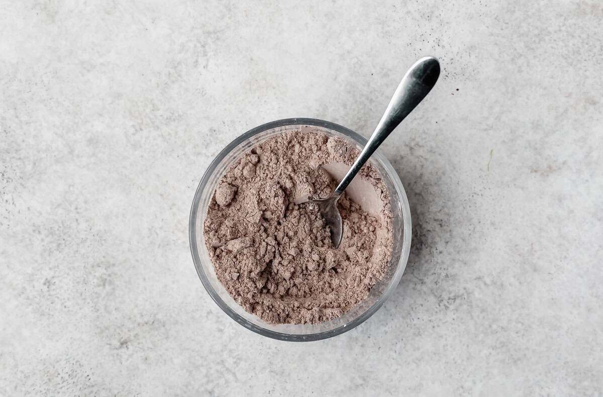 Dry ingredients for brownies in a small bowl with a spoon in it.