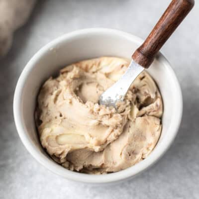 Truffle butter in a small white bowl with a wood handled spreader.