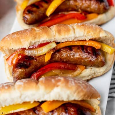 Three grilled sausage and pepper sandwiches close up.