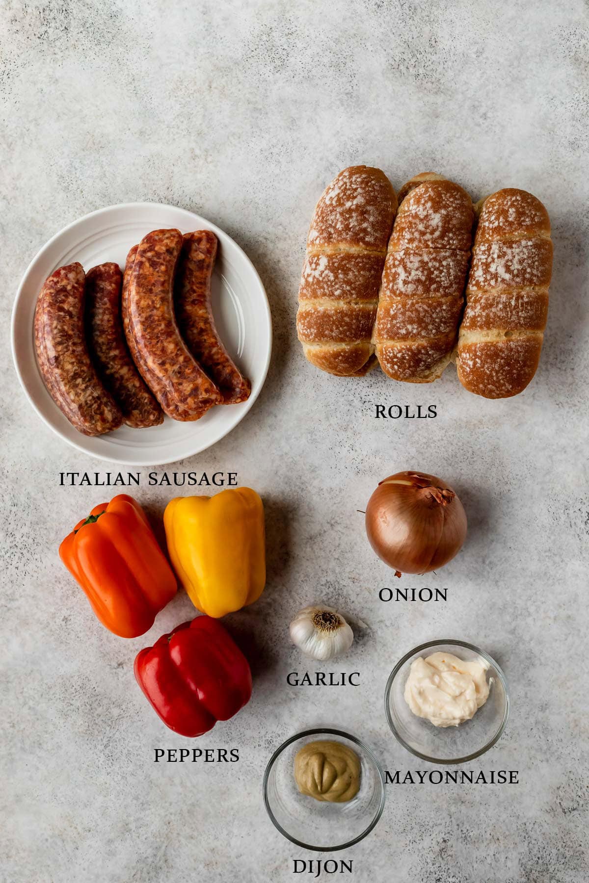 Ingredients needed to make grilled sausage and peppers sandwiches on a light background with text overlay.