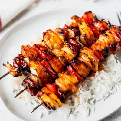 Three Hawaiian Chicken Skewers on a plate of rice.