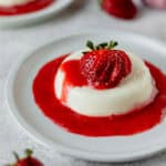 Coconut Panna Cotta topped with strawberry coulis on a white plate.