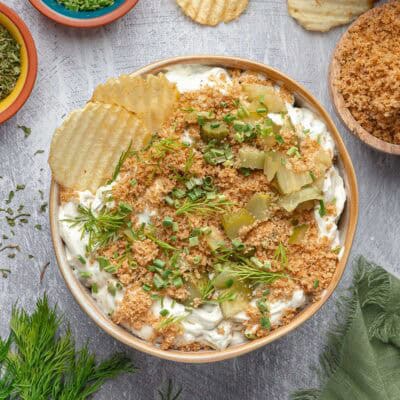 Overhead of a bowl of fried dill pickle dip with potato chips in and around it.