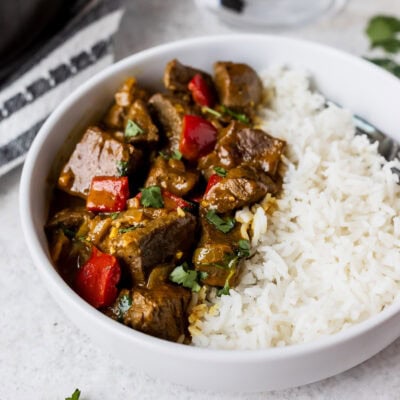 A bowl with half coconut curry beef and half rice.