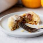 A puff pastry pumpkin roll cut in half on a plate.