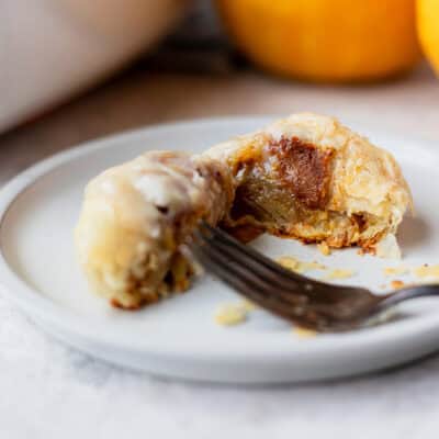 A puff pastry pumpkin roll cut in half on a plate.