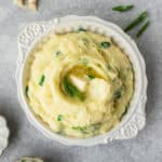 A white bowl filled Irish champ with scallions around it.