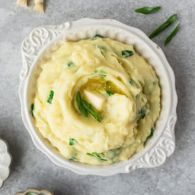 A white bowl filled Irish champ with scallions around it.