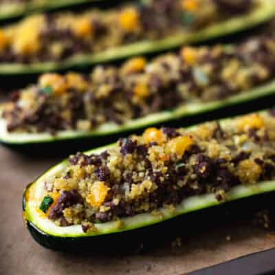 Close up of Moroccan stuffed zucchini boats on a parchment paper-lined baking sheet.
