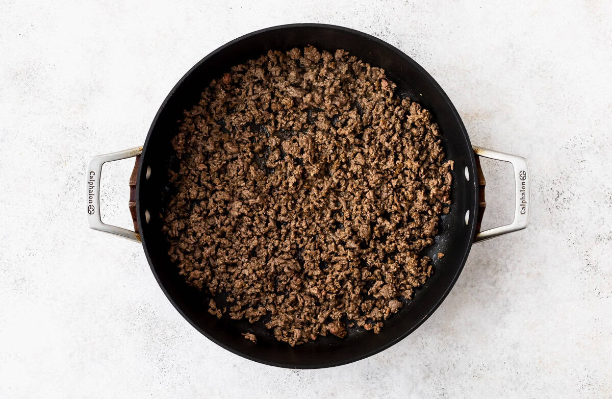 Seasoned ground beef in a large black skillet.