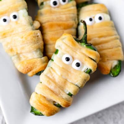 Close up of mummy jalapeno poppers on a white plate.